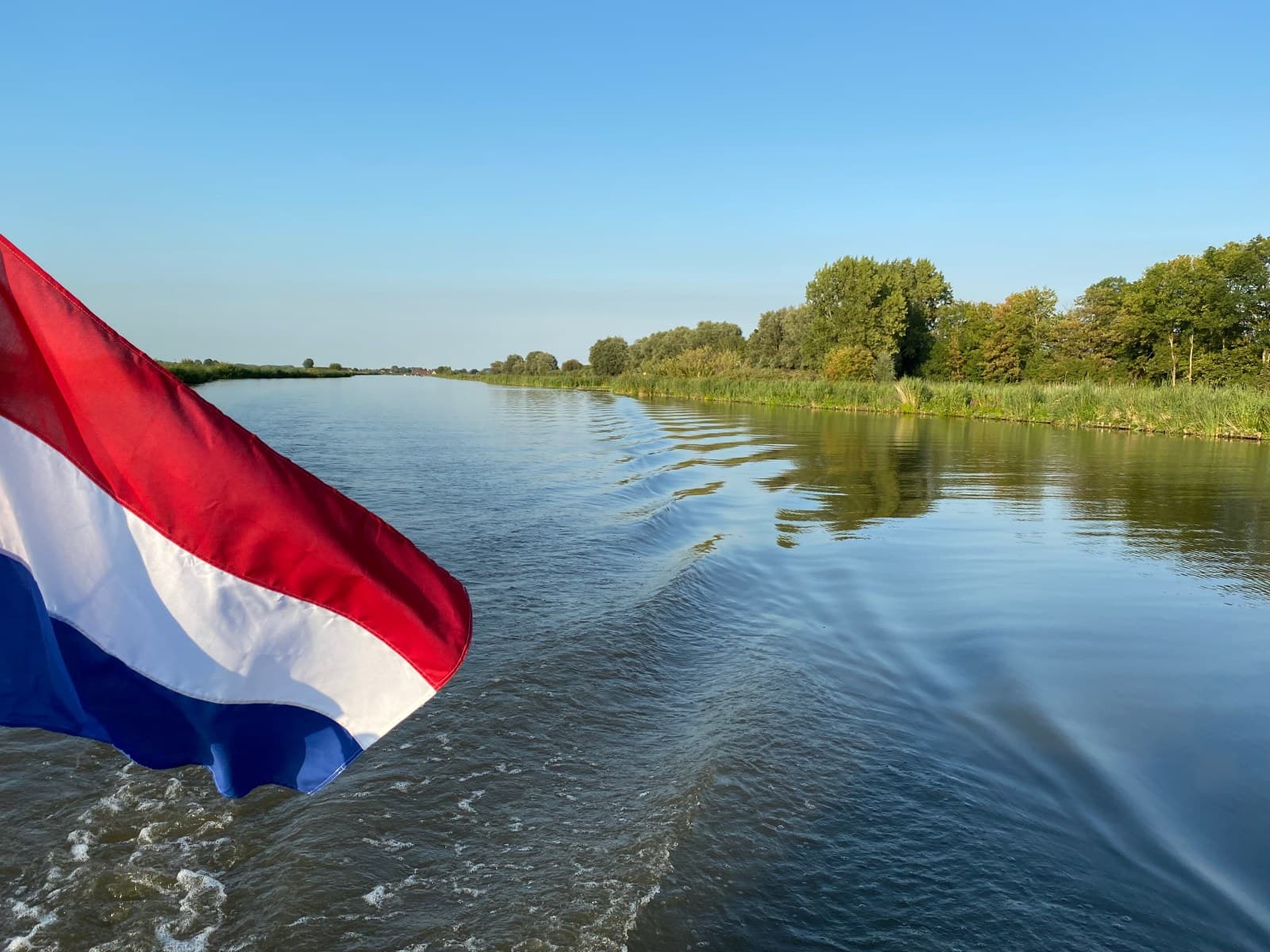 Varen met de Nederlandse vlag over het water van Midden-Delfland